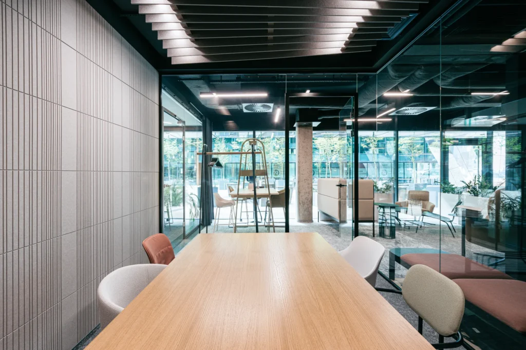 Modern felt wall panels and a felt slatted ceiling in a glass-walled conference room, designed for optimal office acoustics.
